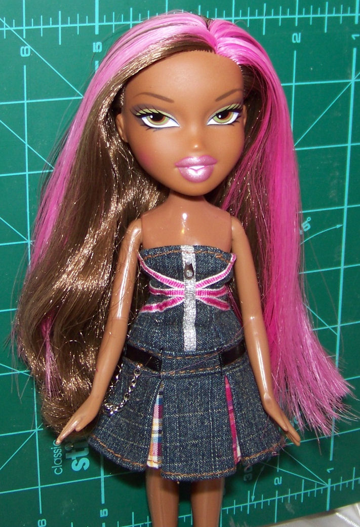 a doll is standing with pink hair and a dress