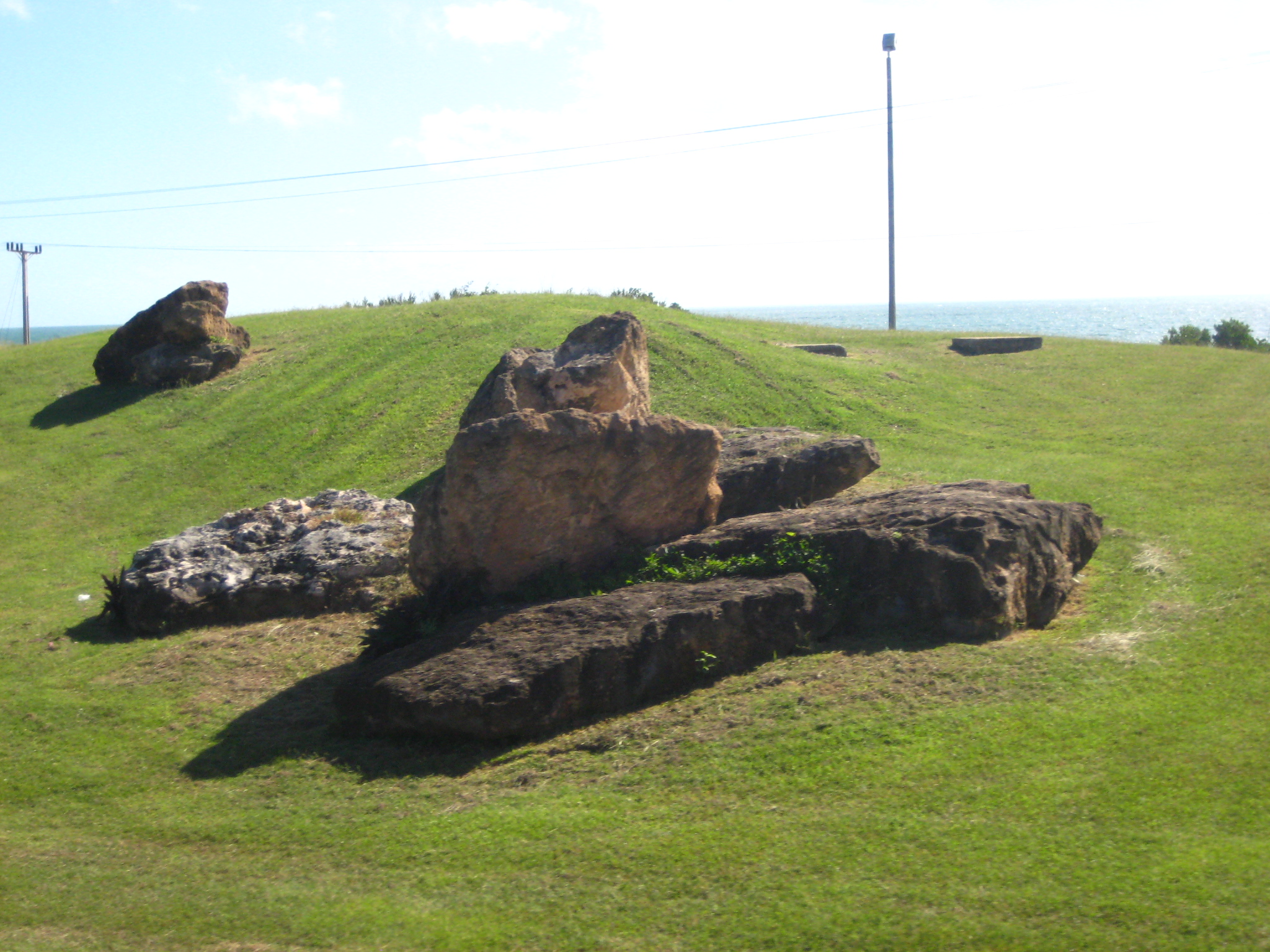 rock formations in grassy area with ocean and sky in background