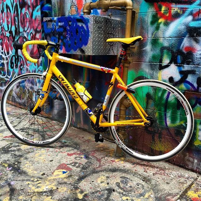 a yellow bicycle parked next to graffiti covered walls
