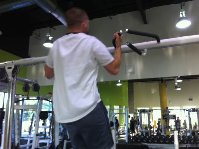 a man using the pull up bar at a gym