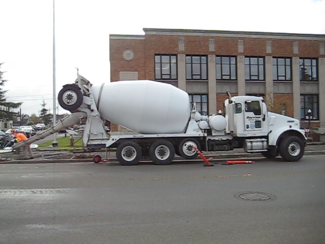 there is a white concrete truck parked by the curb