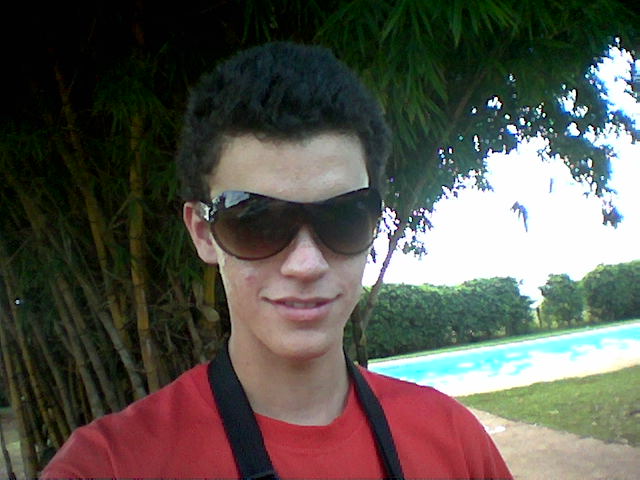 man in red shirt and sunglasses by a swimming pool
