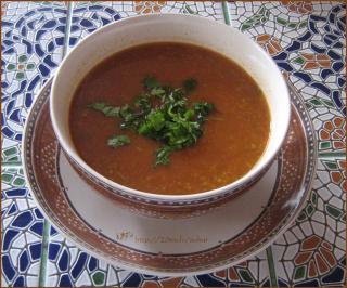 a bowl of red lentula soup with fresh herbs