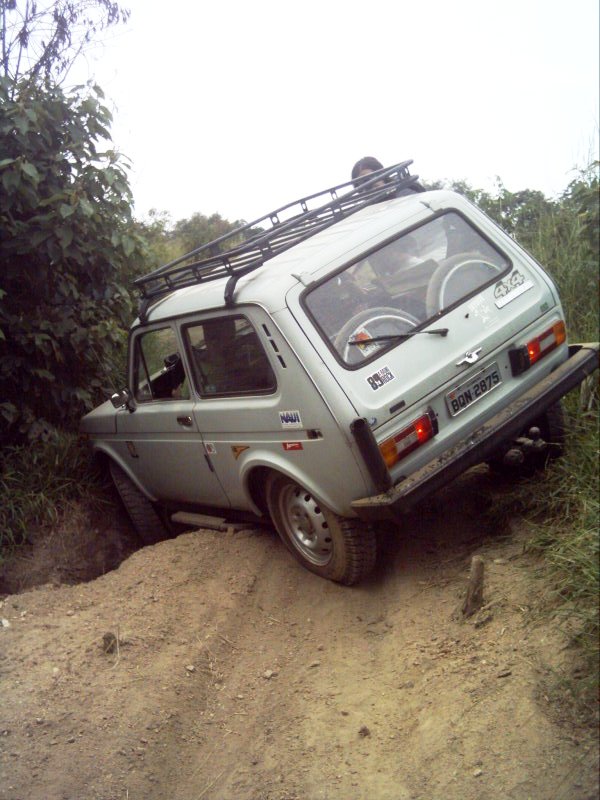 small suv on steep terrain with trees behind