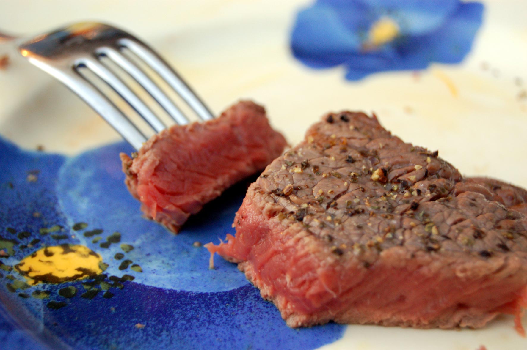 a fork and piece of steak on a plate