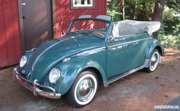 a large green and white beetle parked outside a red house