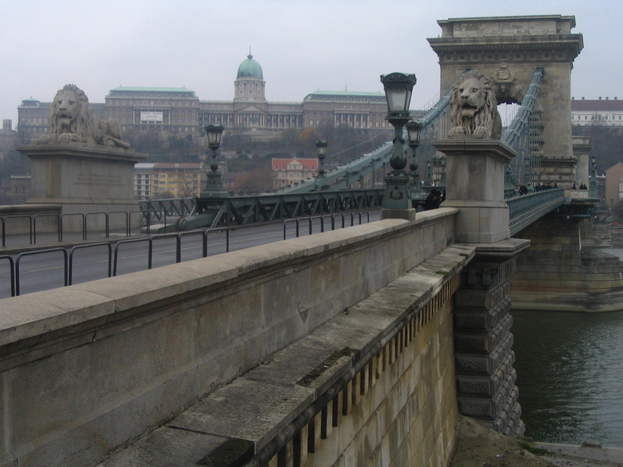 people walk along a walkway and bridge with a view of the river