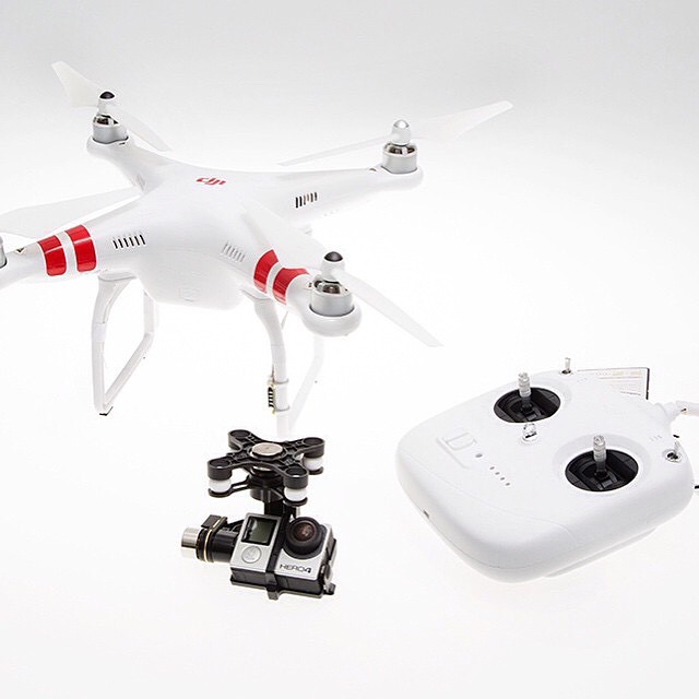 white quadcopter on a white background next to a tripod, two cameras and a smartphone