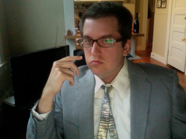 a man in glasses wearing a gray suit and tie