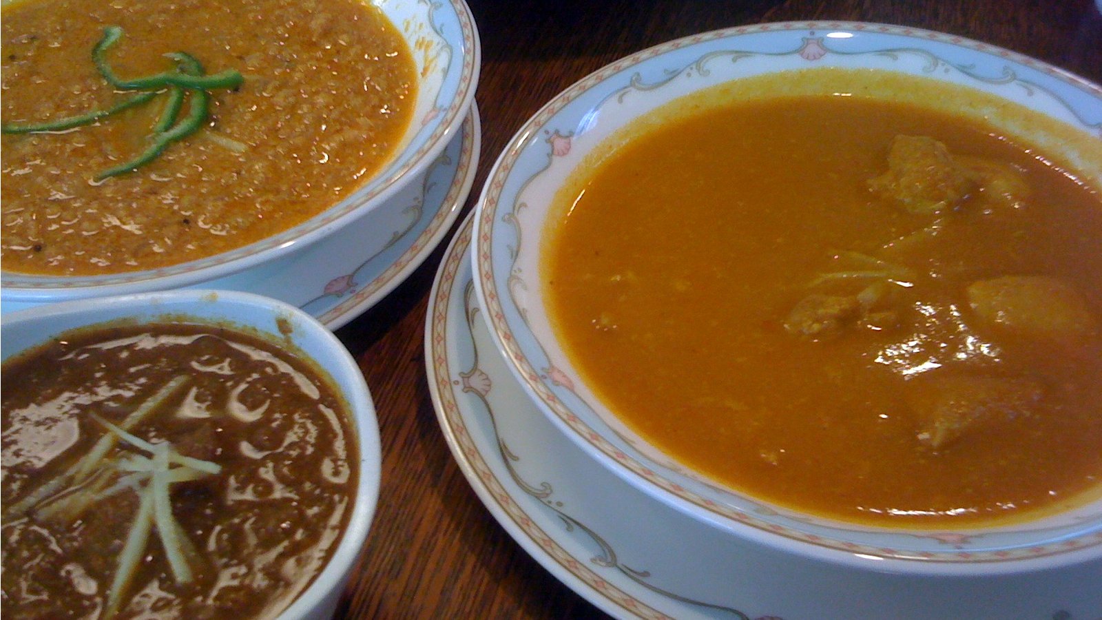 three bowls of soup sit next to each other