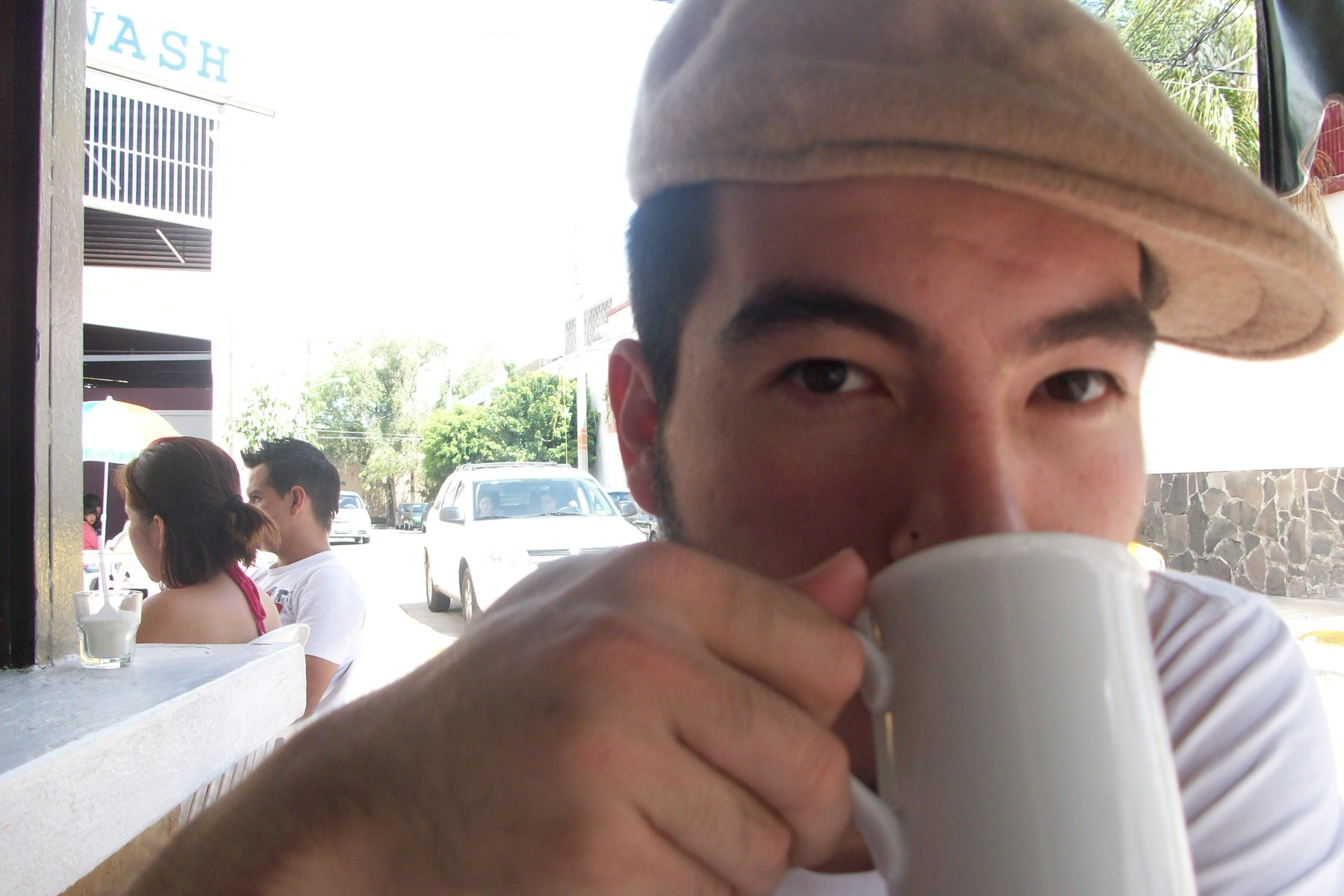 a man drinking a cup outside with a group of people behind him