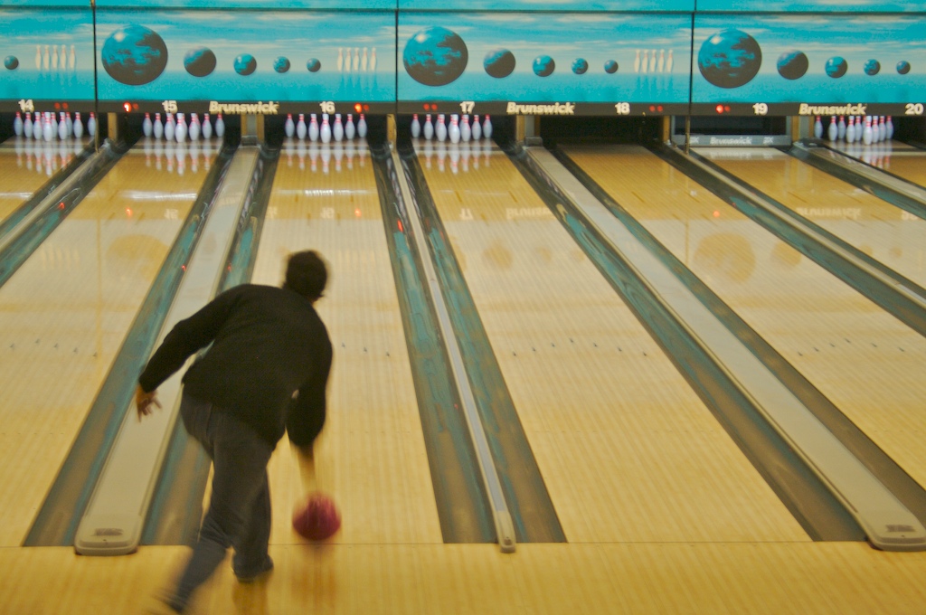 a man standing next to bowling lanes holding a ball