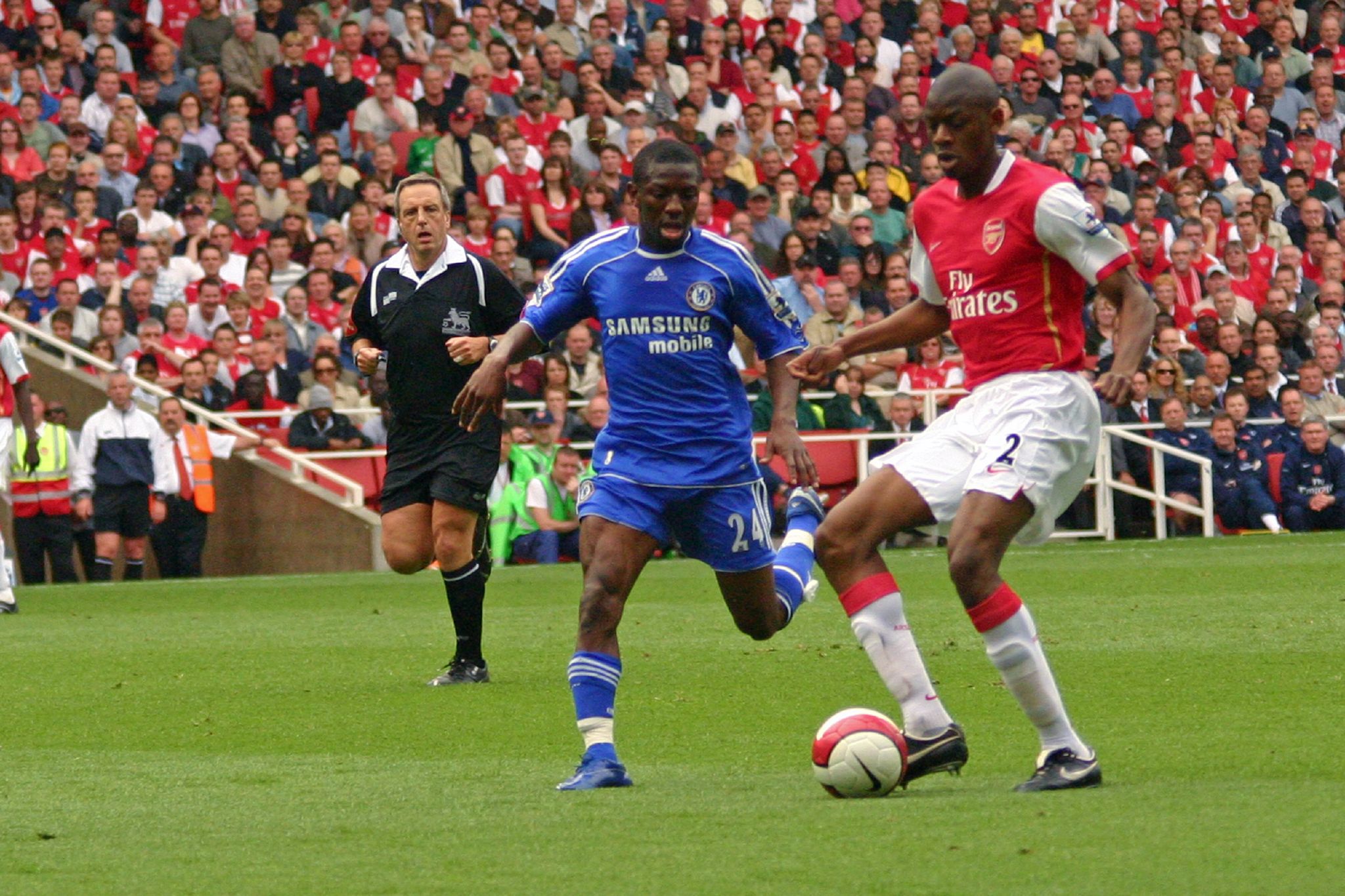 soccer players chase the ball in front of a packed stadium