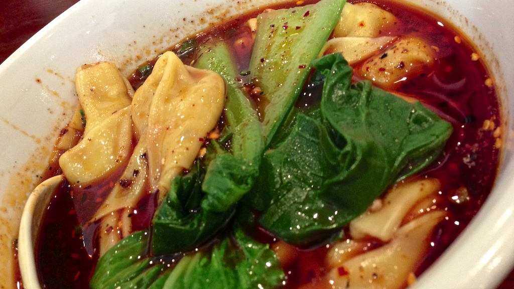 a bowl of food has noodles, spinach and sauce