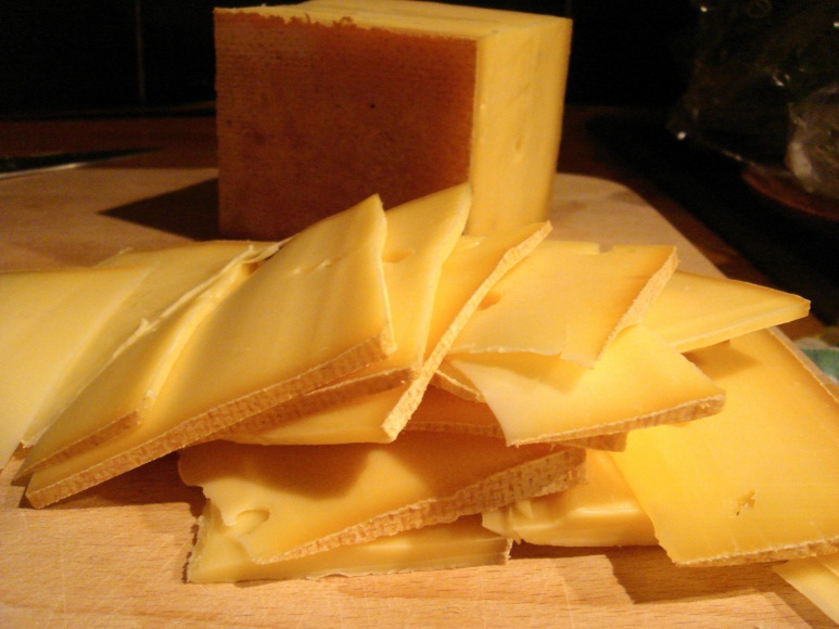 some type of cheese cut and stacked on a wooden surface