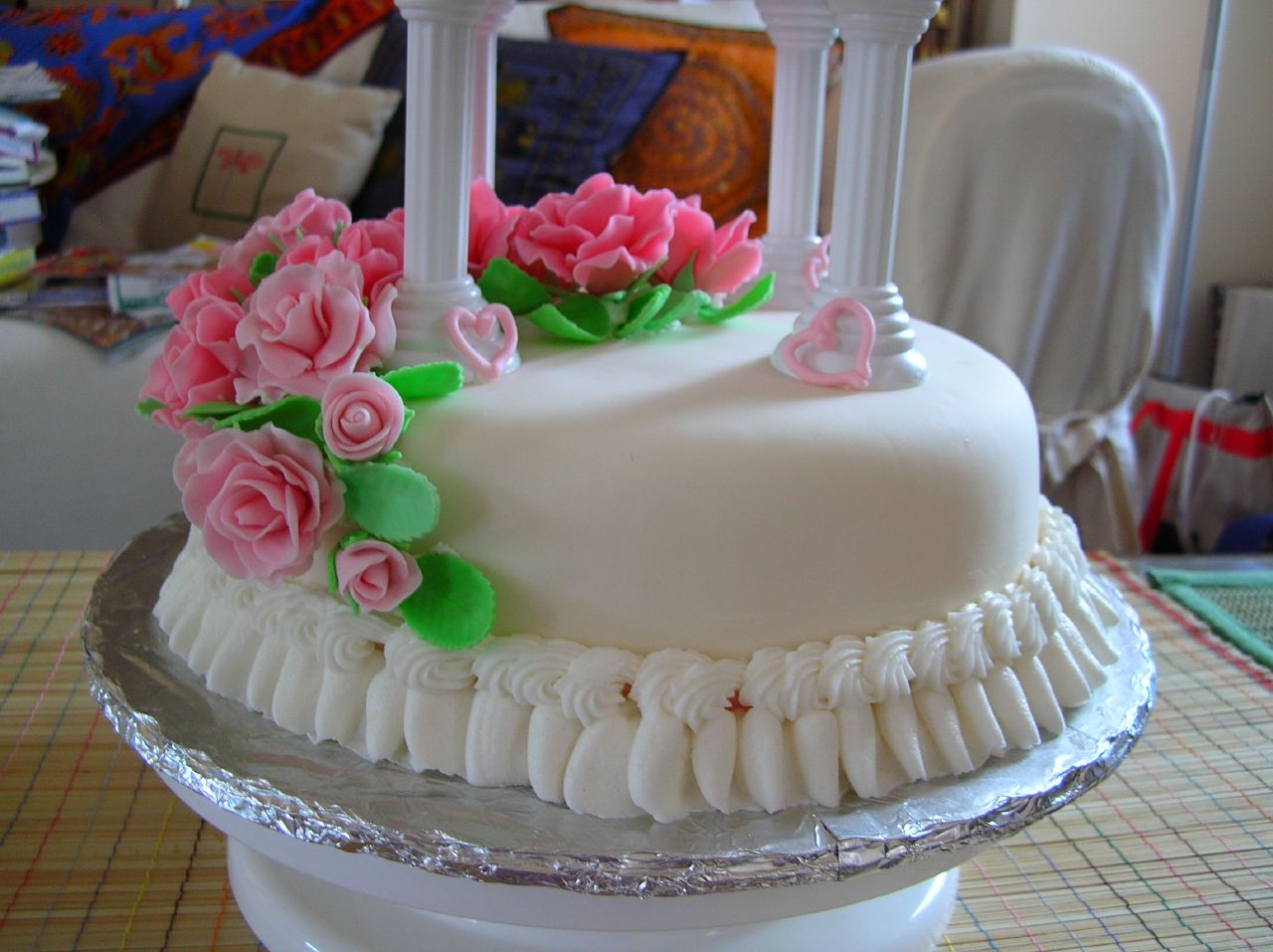 the small white cake has pink roses on it