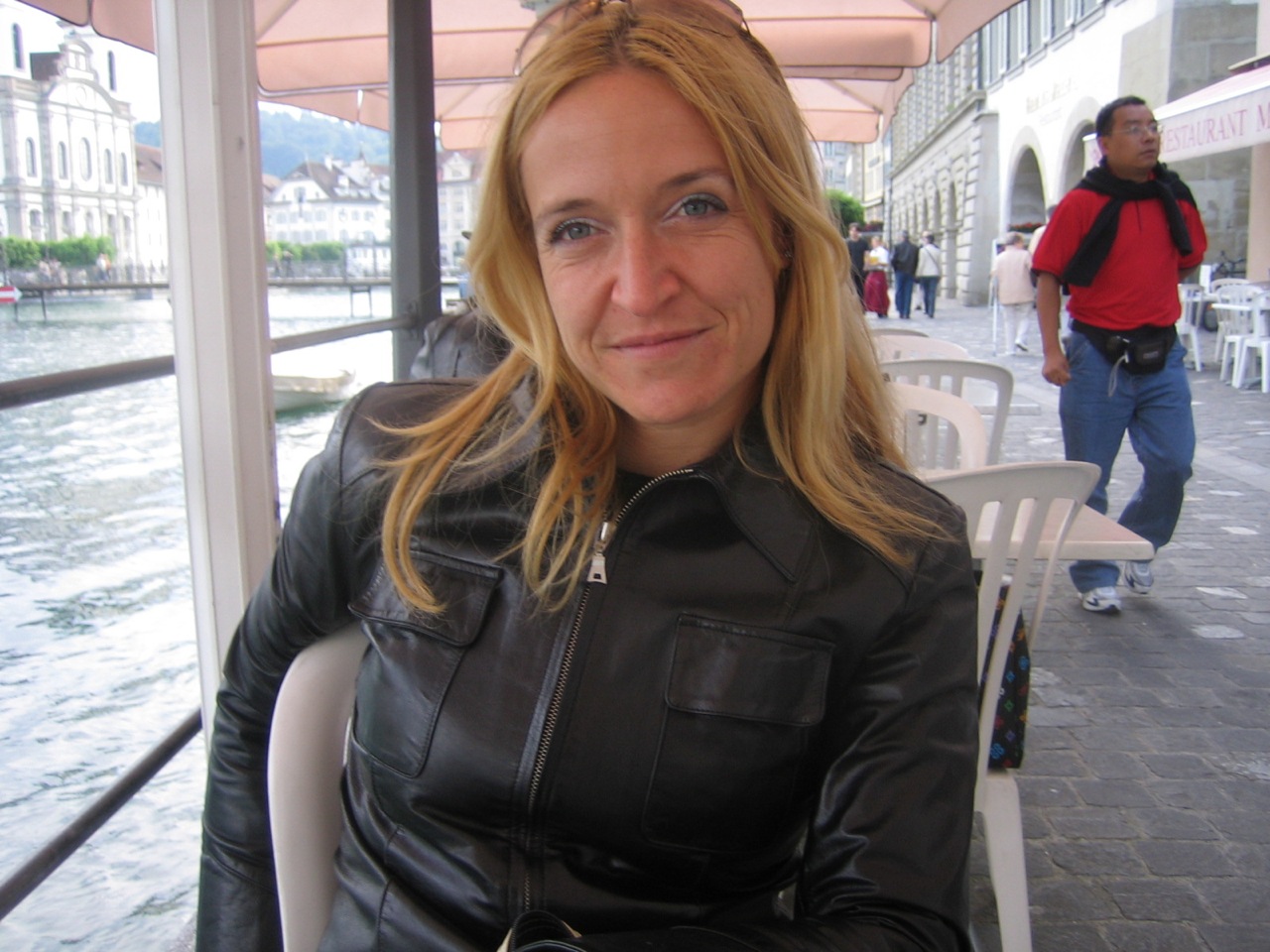 a beautiful blonde woman sitting at a table in a leather jacket