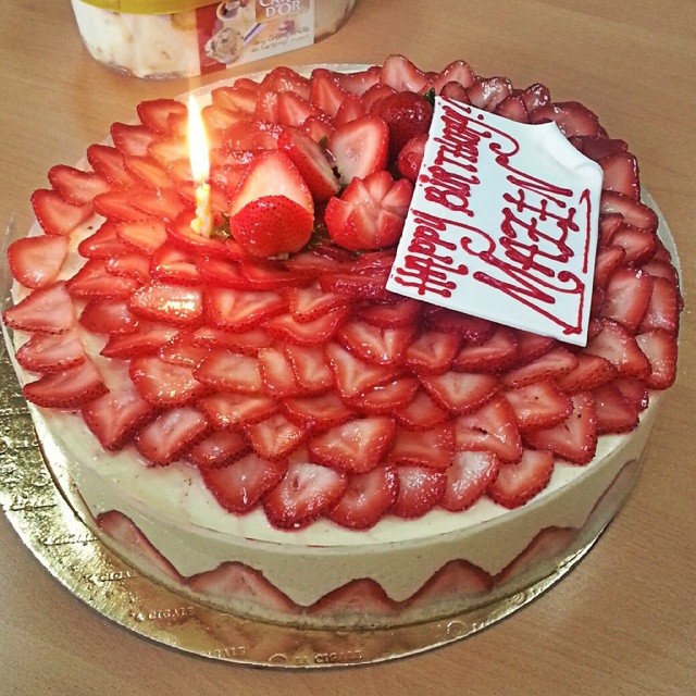 a birthday cake with strawberries topped by a candle