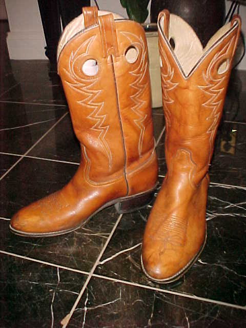 pair of old western boots sitting on a tiled floor