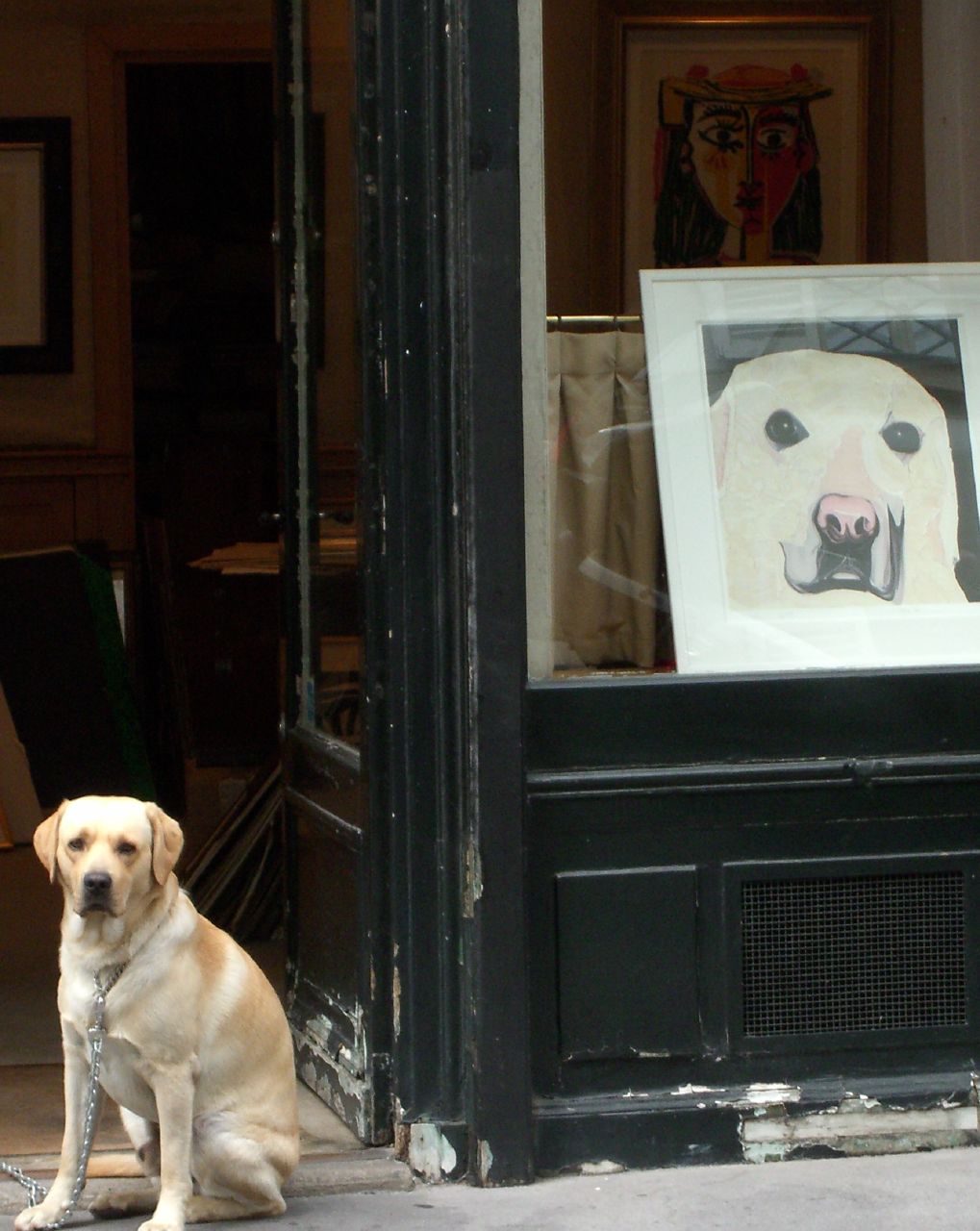 a dog sitting in front of a doorway near a painting