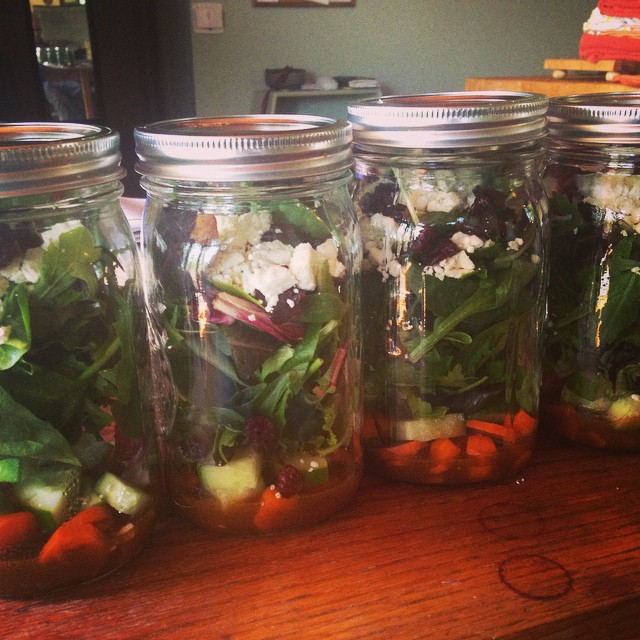 four mason jars full of various vegetables on a table