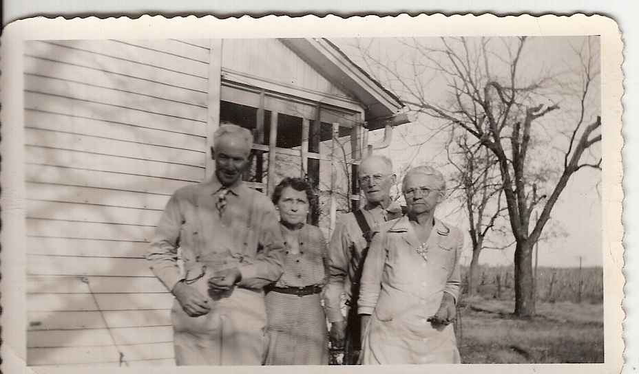 this is an old po of a man and three people standing in front of a house