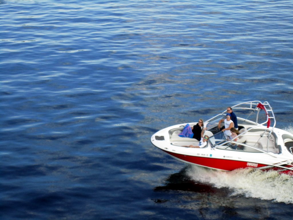 three people on the front of a speed boat going through water