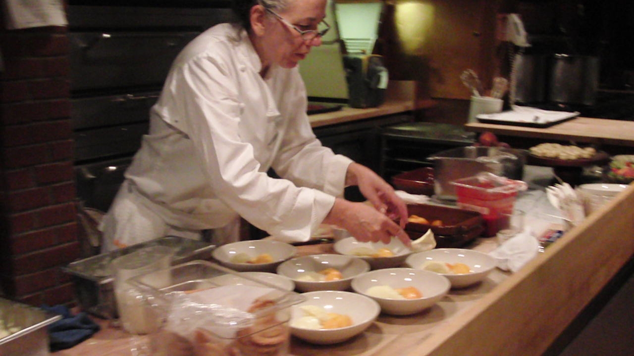 a man in white cooking on top of a wooden counter