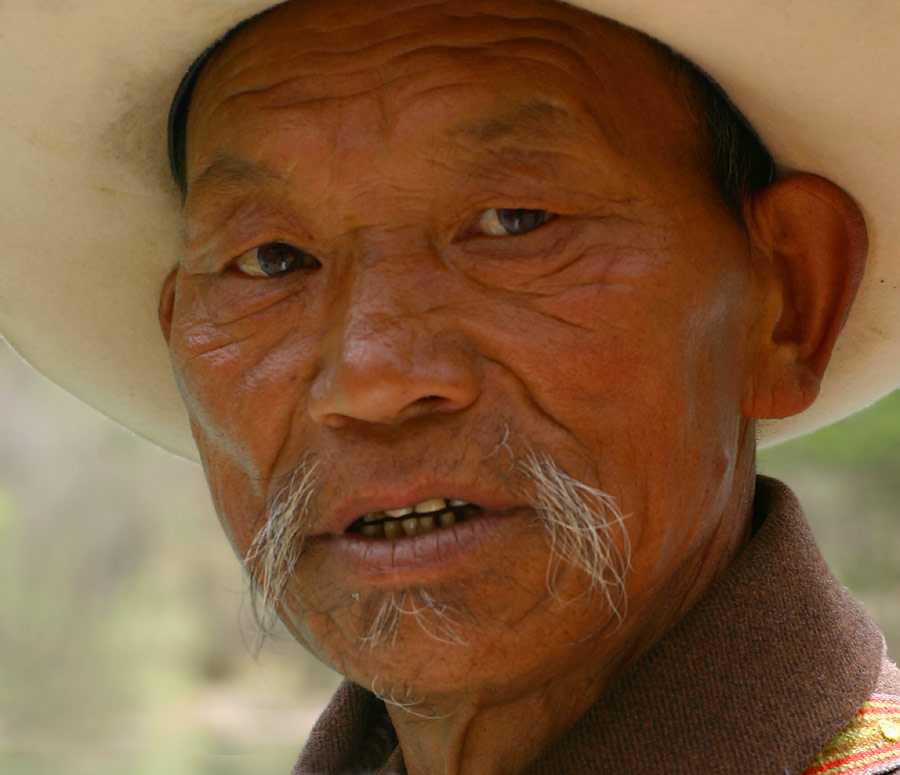 the head of an older man with a white hat
