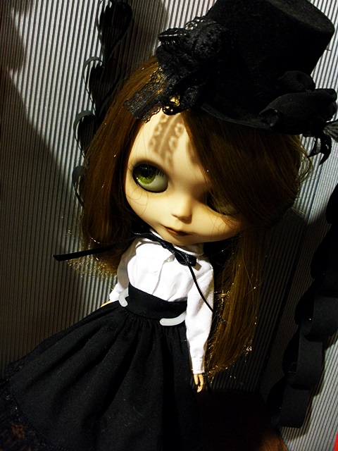 a doll is wearing a black hat with long hair