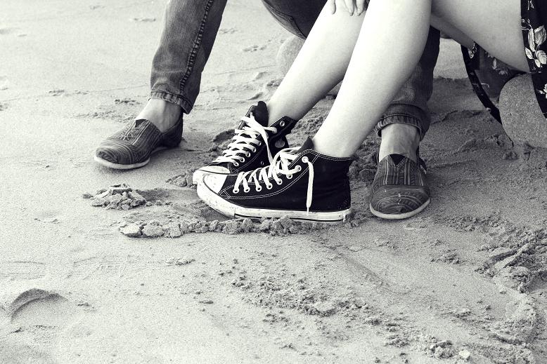 two people sitting next to each other on a beach