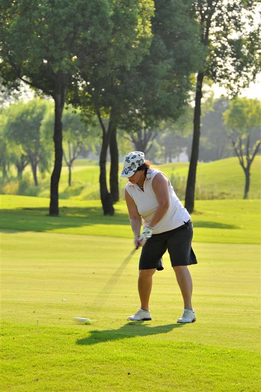 a women golf player swings her club at the ball