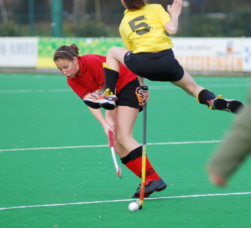 women playing field hockey during match on the green