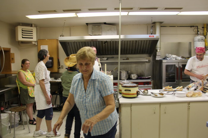 several people standing in the kitchen and cooking
