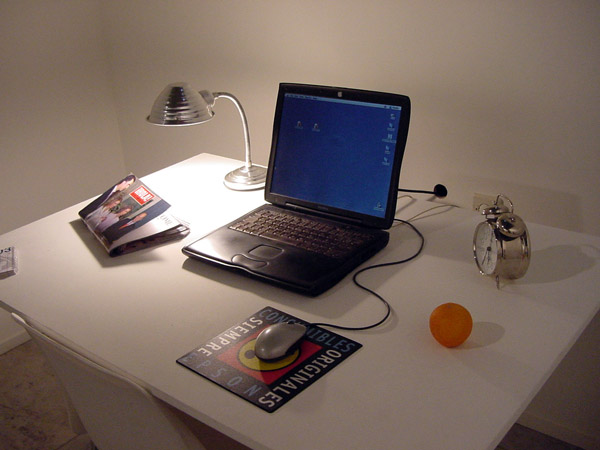 the laptop on the small desk is near an alarm clock