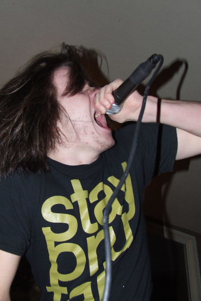 a guy with long hair holds his microphone up to take a pic