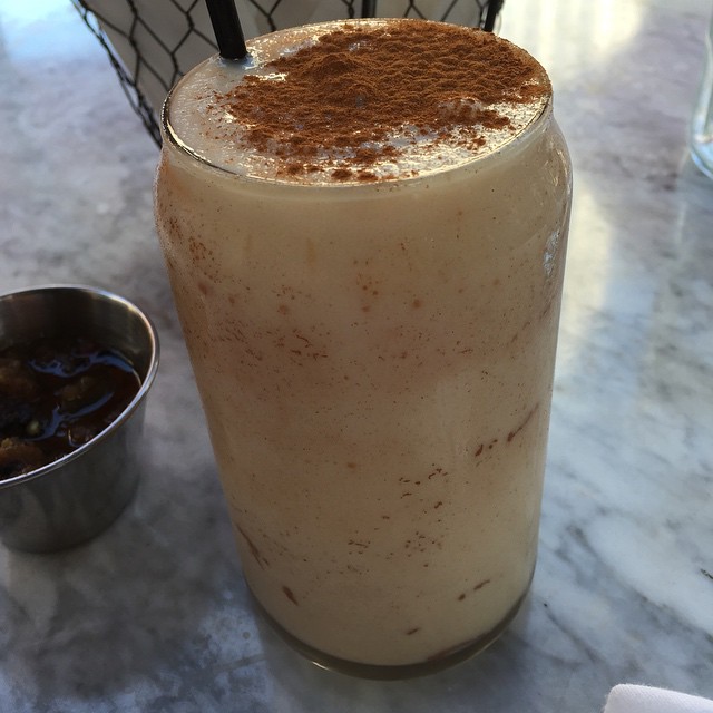 a drink with cinnamon sprinkles and a drink container sitting beside it