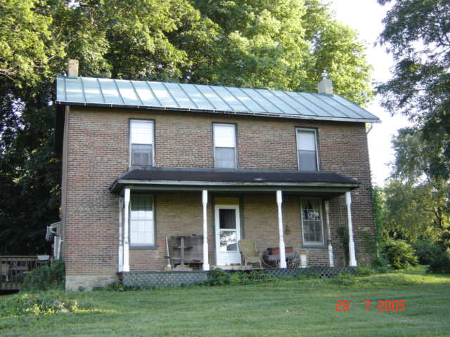 the front of a brick house with a black metal roof and front porch