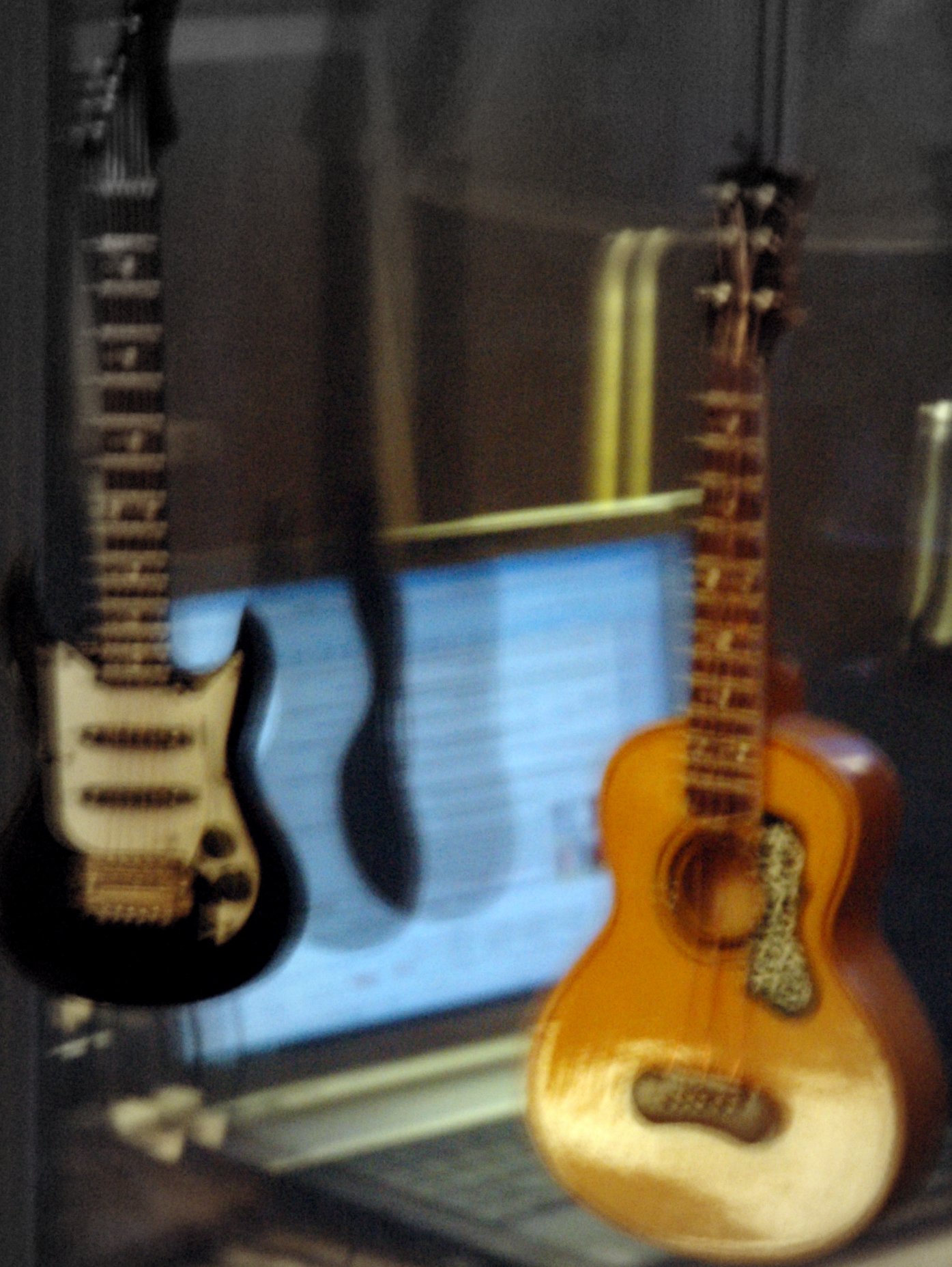 two guitars are next to each other in front of a monitor