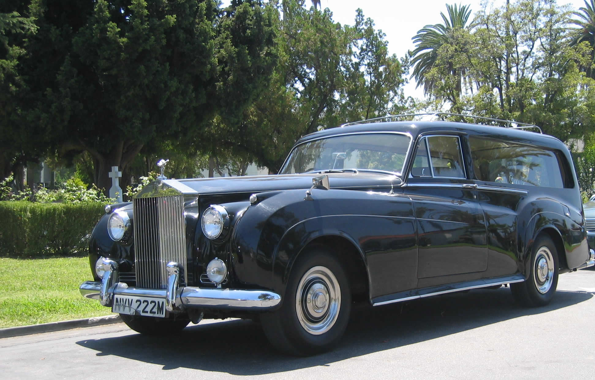 a vintage black car is sitting next to some trees