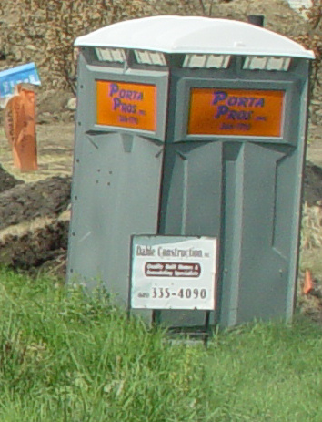 a toilet sitting next to another toilet in a yard