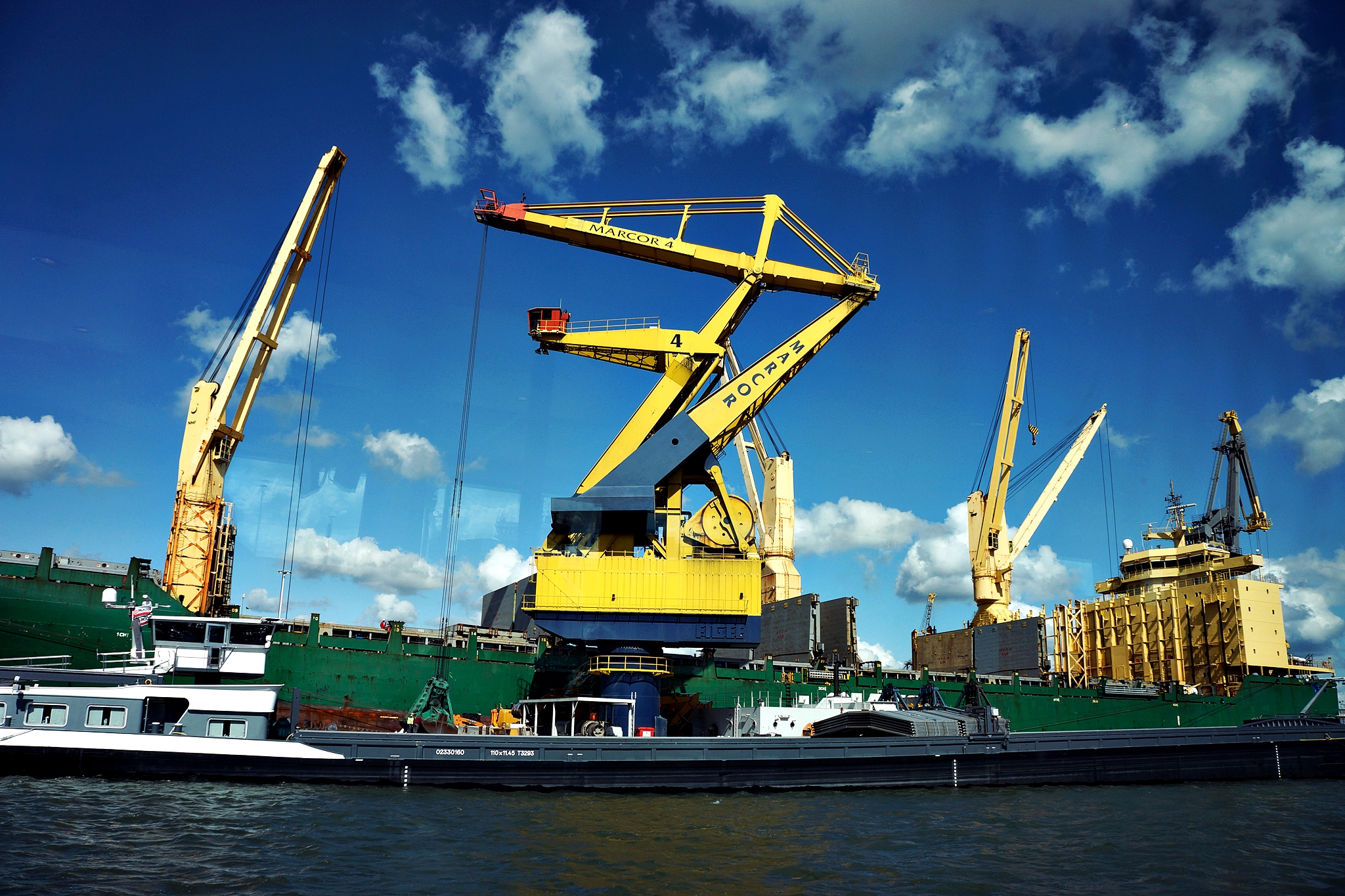 two cranes in front of a large tug boat