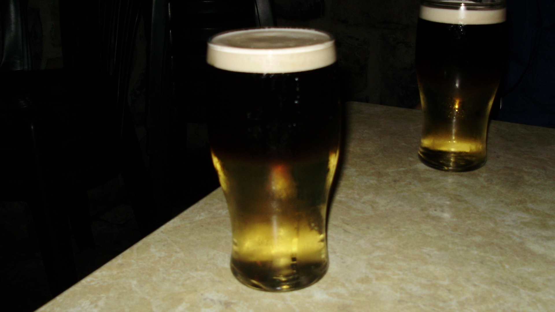 two large dark mugs on a table near some drinks