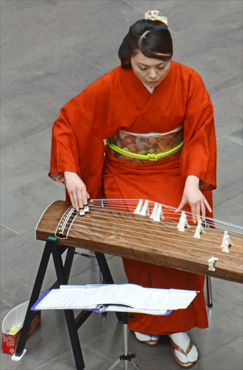 an asian woman in a red costume playing musical instruments