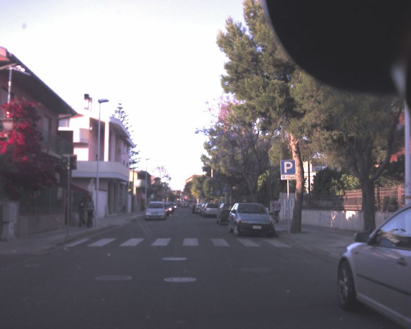 cars driving on a street next to several houses