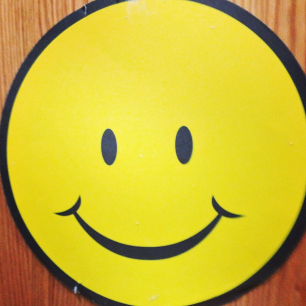 a yellow smiley face sign is on the wall