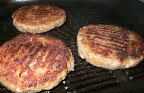 three hamburger patties cooking on the grill