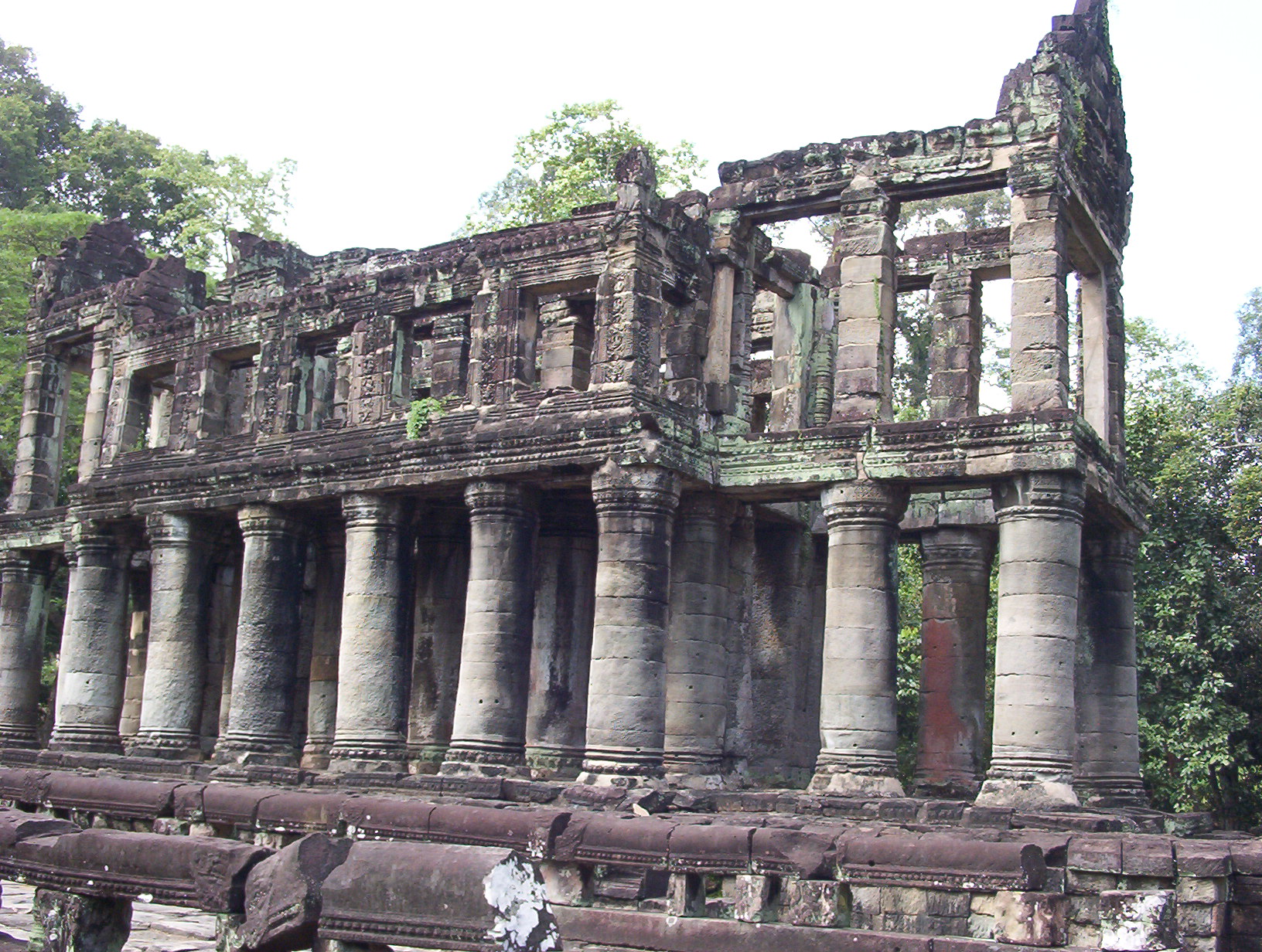 a po of an old building with many pillars and trees in the background