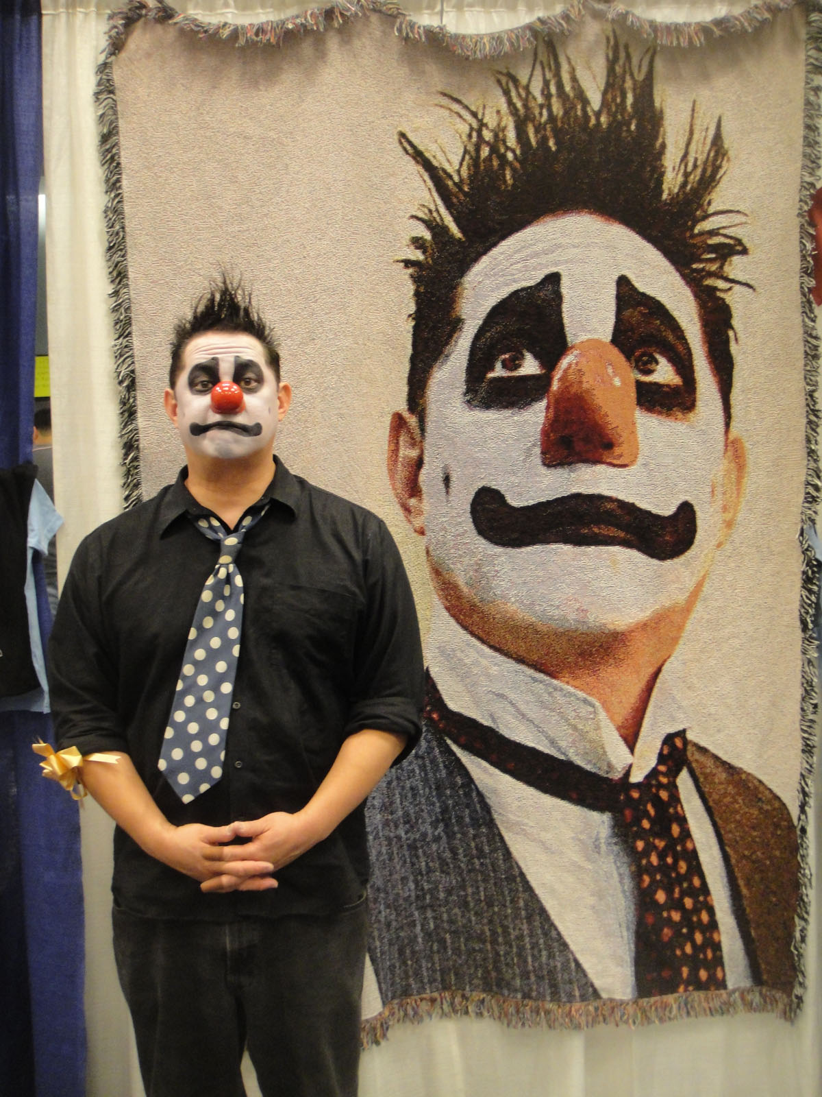 a guy in clown face paint standing in front of a tapestry