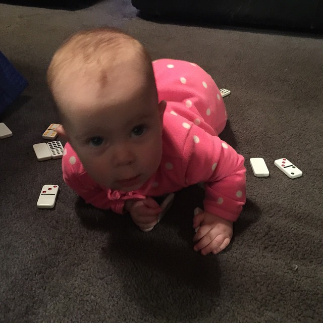 a baby crawling on the floor looking up at playing cards
